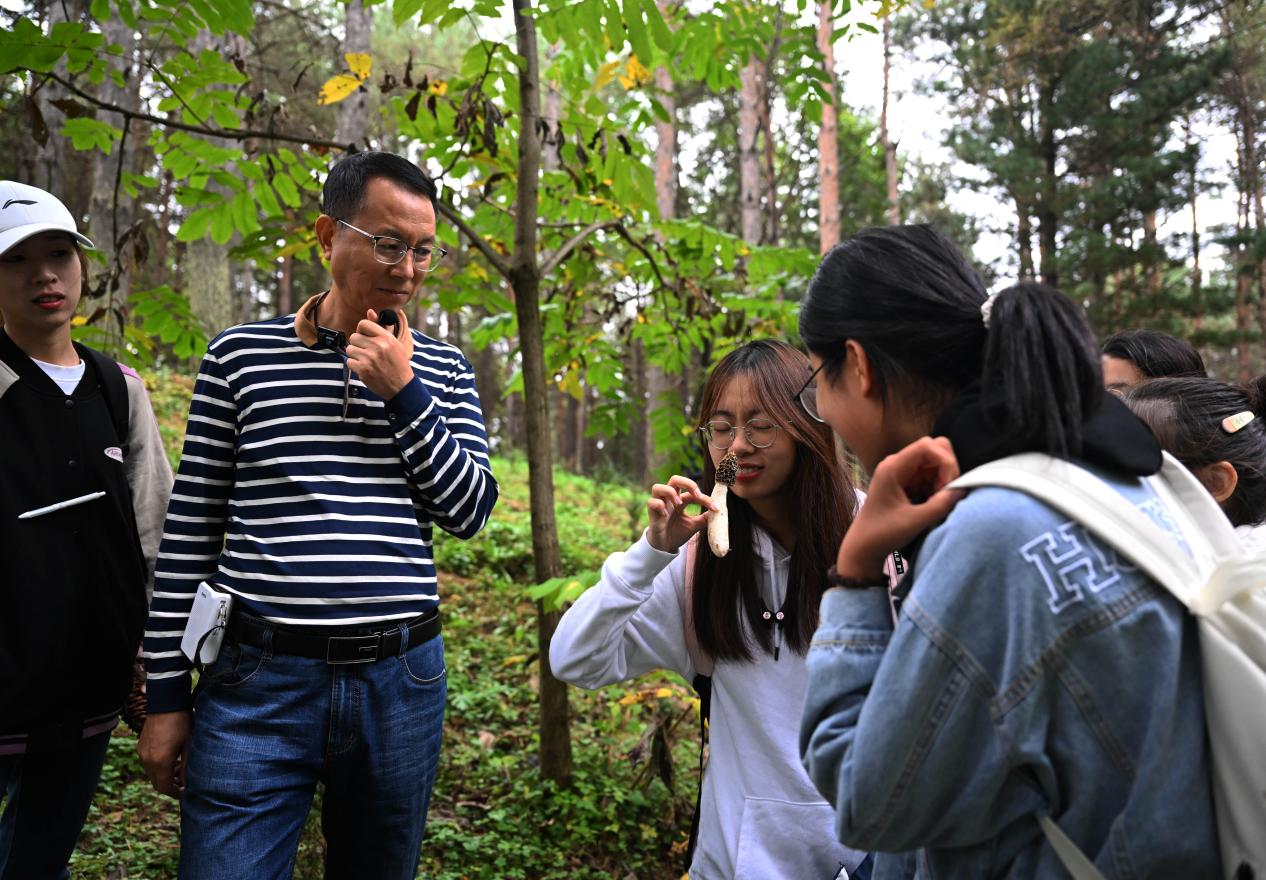 王占斌老師給同學(xué)們講解辨識蘑菇。（學(xué)校供圖）.jpg