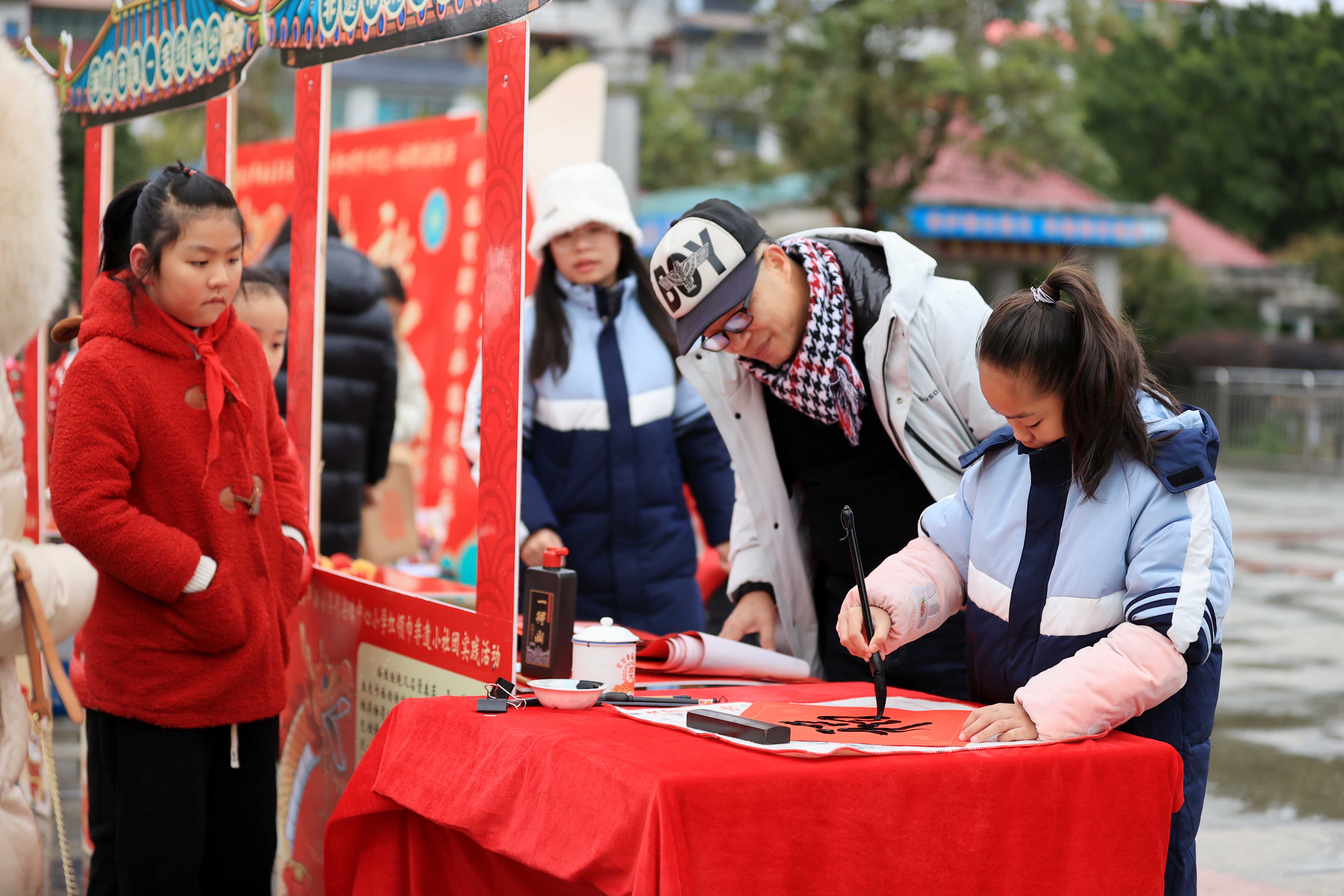 圖10：1月20日，在廣西柳州市融安縣長(zhǎng)安廣場(chǎng)，一名小學(xué)生在書寫福字，準(zhǔn)備贈(zèng)送市民。（譚凱興 攝）.JPG