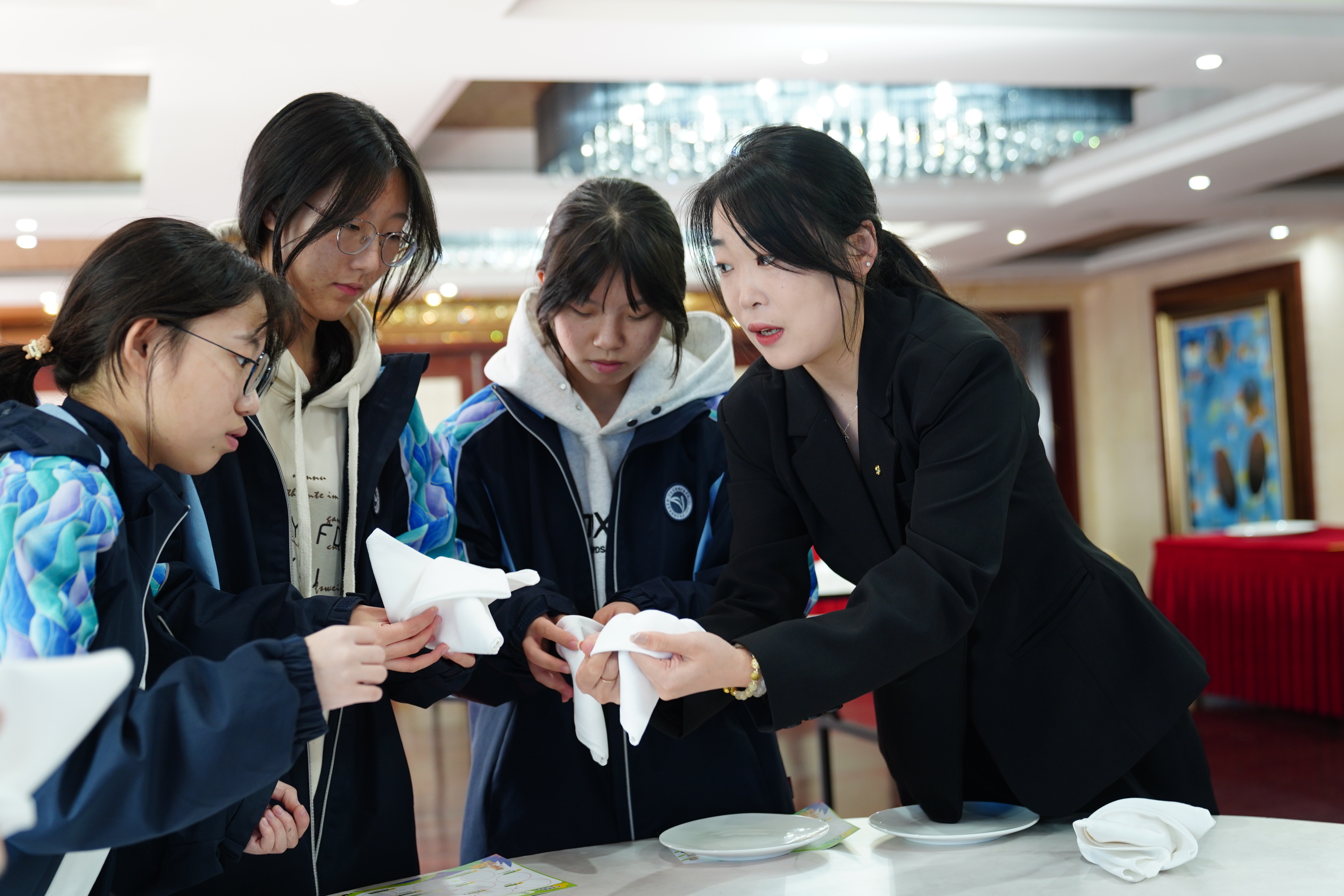 寧波東錢湖旅游學校學生在企業(yè)導師（右一）的指導下體驗指尖藝術(中餐擺臺)項目 胡佳 攝.jpg